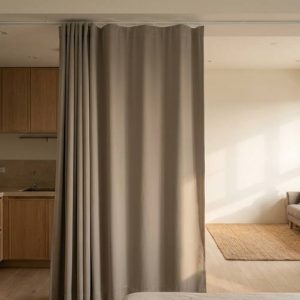 Open-plan living area with a kitchen on the left and a dining area on the right, separated by a gray curtain.